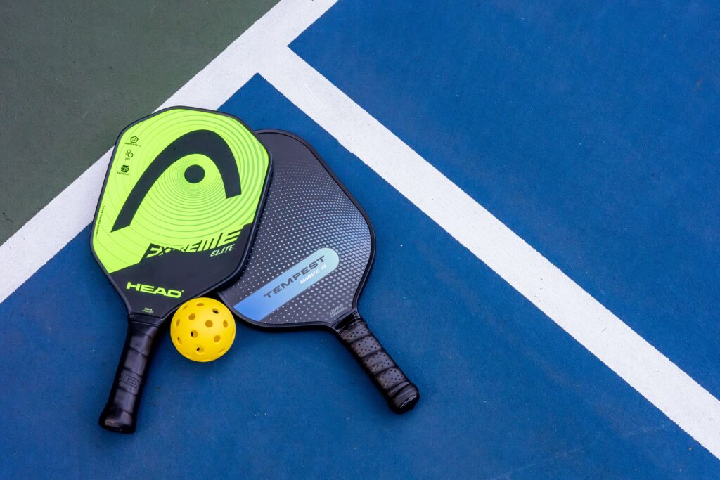 Top down view of paddles and balls for pickleball laid on a blue mat